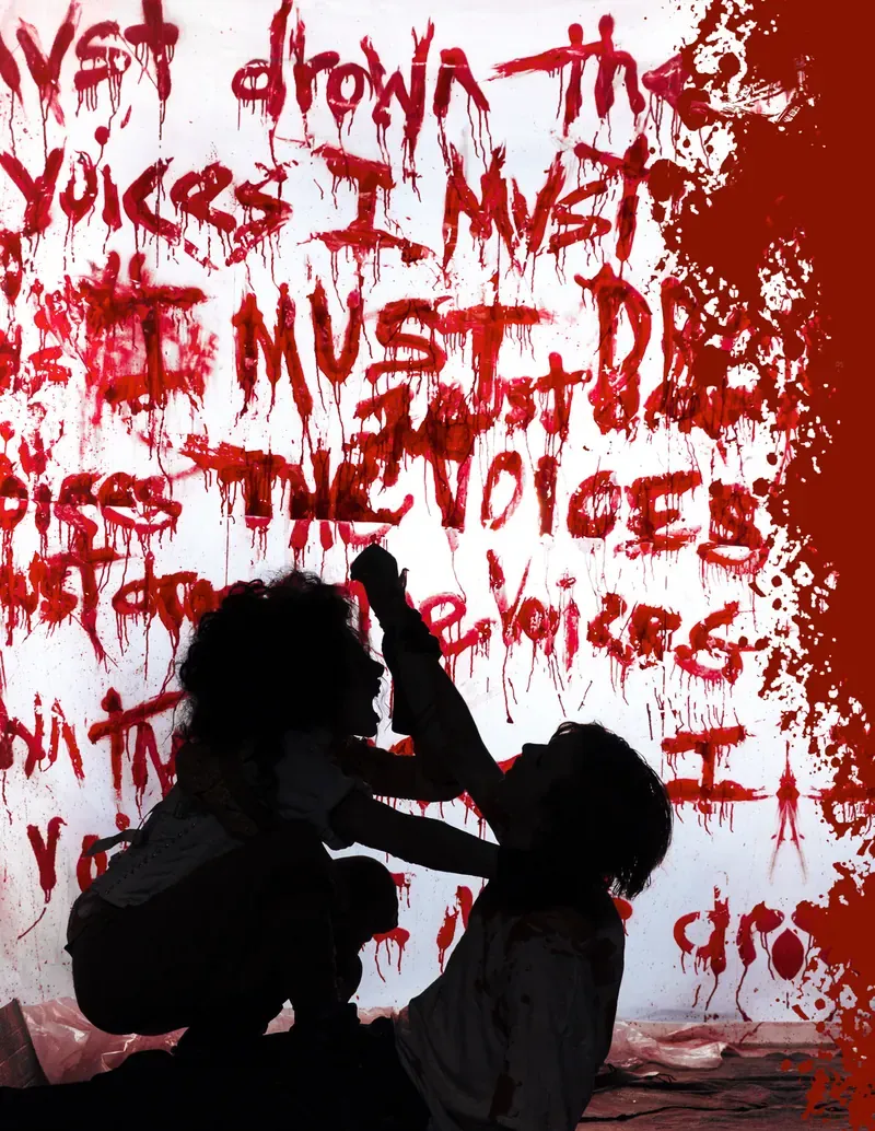 Un muro bianco coperto di scritte rosse colanti, tracciate col sangue, e davanti due figure in controluce, chine l’una sull’altra